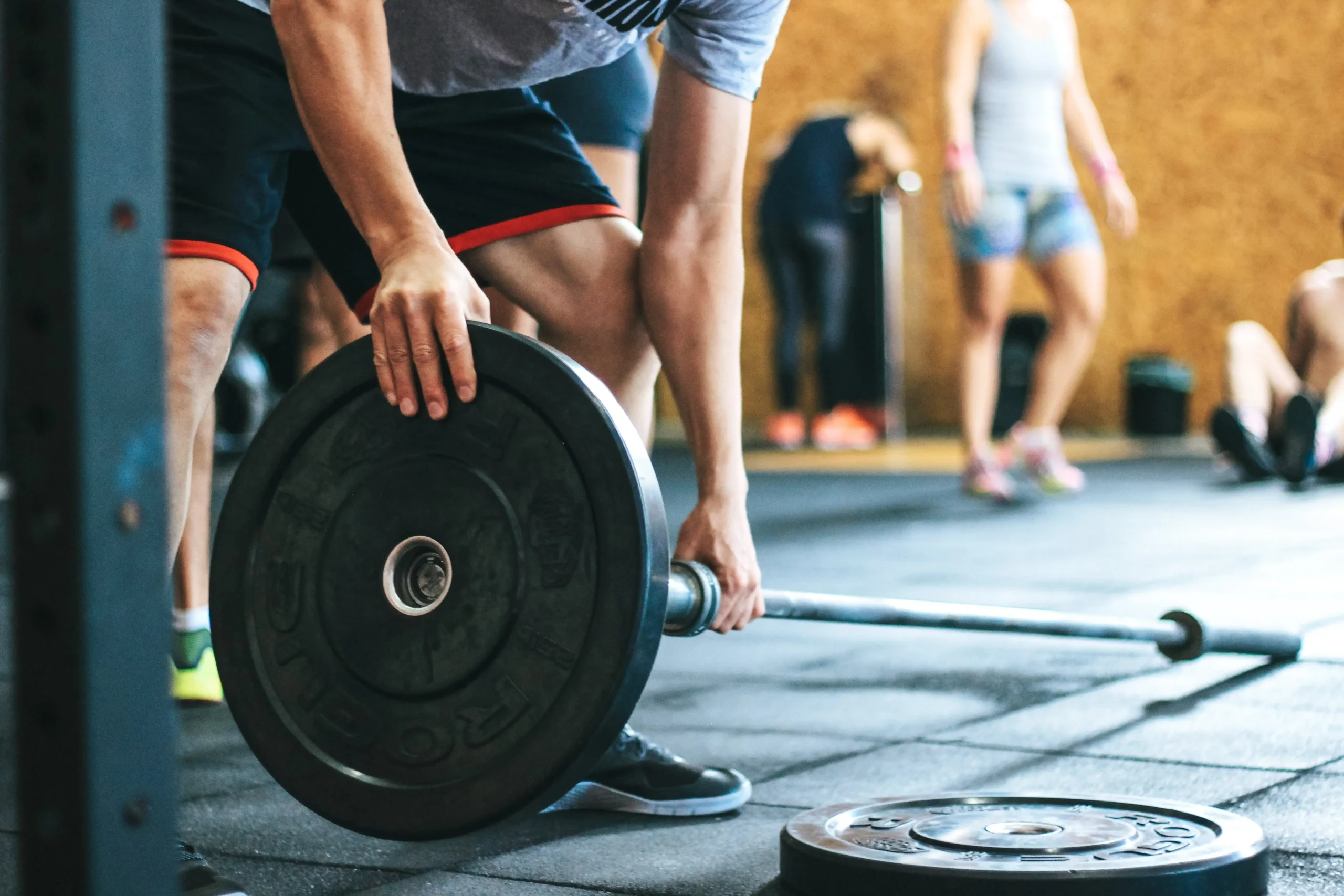 A man attaching plates onto a barbell in a gym