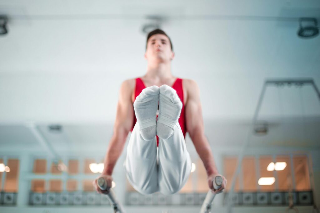 A gymnast performing a L-sit on a parallel bars