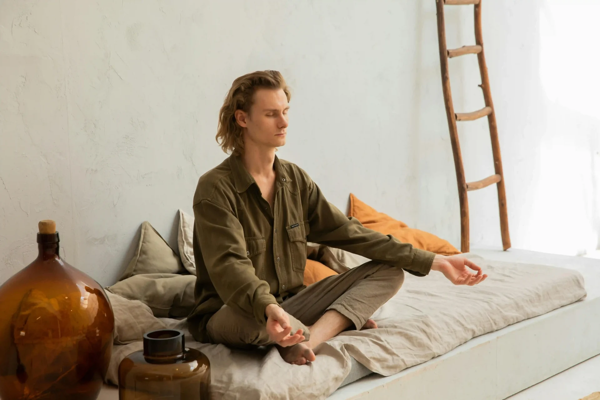 Concentrated man meditating in Lotus pose on mattress
